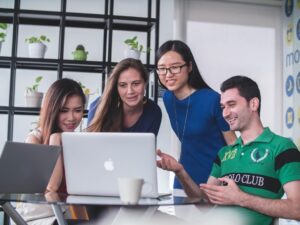 Team members collaborating at a computer to enhance efficiency and response time through automated proposal creation